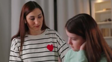 Çizgili kazaklı bir kadın, üzgün kızına bir şey anlatıyor. Annem okulda kötü not alan kızını teselli ediyor. Yüksek kalite 4k görüntü