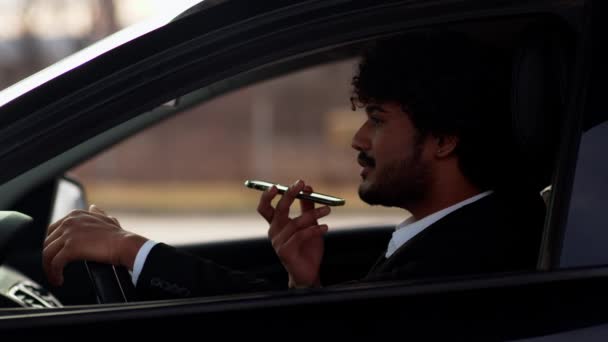 若いインド人ビジネスマンが車の中に座り 渋滞に巻き込まれることに不安を感じている 車の中でビジネススーツの巻き毛の男が電話で話している 高品質4K — ストック動画