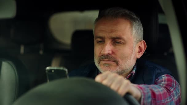 Brodaty Mężczyzna Koszuli Kratę Siedzi Samochodzie Patrzy Coś Przez Telefon — Wideo stockowe