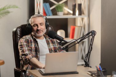 Podcast blogcusu mikrofonla konuşuyor. Kulaklıklı yaşlı adam video kaydediyor. Yüksek kalite fotoğraf