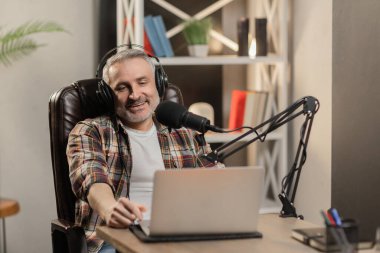 Gülümseyen blogcu evden podcast yapıyor. Çevrimiçi işçi gülümseyerek video kaydediyor. Yüksek kalite fotoğraf