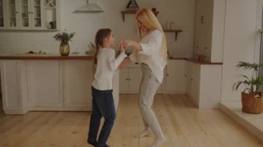 Anne ve kızının evde dans ederken el ele tutuşmalarını uzun uzun izlemek. Genç bir kadın çocuğuyla eğleniyor. Yüksek kalite 4k görüntü