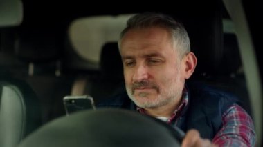 Ekose gömlekli bir adam arabada oturur ve akıllı telefon ekranına dikkatle bakar. Arabanın sürücüsü akıllı telefondan iyi haberi okuduktan sonra sevinmeye başlar. Yüksek kalite 4k görüntü