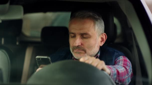 Mężczyzna Średnim Wieku Siedzi Samochodzie Patrzy Ekran Smartfona Siwowłosy Mężczyzna — Wideo stockowe