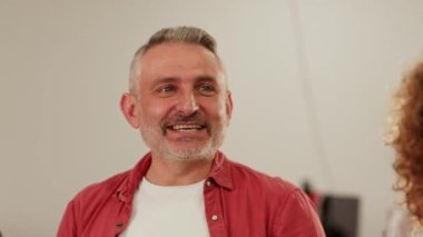 Şirketin müdürü, çalışanlarıyla birlikte ofiste küçük bir parti verdi. Kırmızı tişörtlü gri saçlı bir adam kadeh kaldırıyor ve iş arkadaşlarıyla alkollü içkiler içiyor. Yüksek kalite