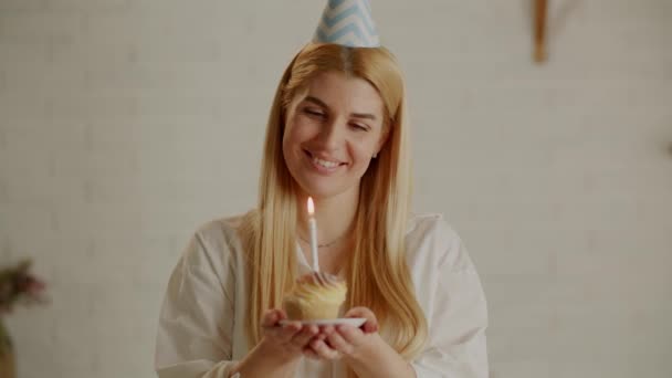 若いきれいな女性が願い事をし ケーキの上にろうそくを吹き消す 将来のための計画と希望の実装 高品質4K映像 — ストック動画