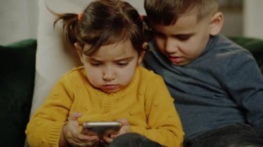 Mutlu şirin küçük çocuk kardeş komik mobil uygulamalar kullanıyor, çevrimiçi oyunlar oynuyor, ebeveyn kontrolü olmadan zaman geçiriyor, modern teknoloji bağımlılığı kavramı. Yüksek kalite 4k