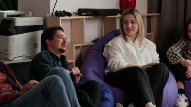 Ofis çalışanları minderlere oturur ve bir şeyler konuşurlar. Bir grup meslektaş mola sırasında birbirleriyle iletişim kurarlar. Yüksek kalite 4k görüntü