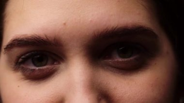 Yeşil gözlü ve kalın siyah kaşlı genç bir kız. Açık tenli genç bir kadın yeşil gözleriyle bakar. Yüksek kalite 4k görüntü