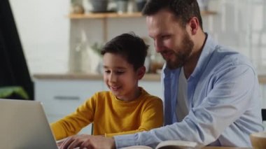 Baba oğluna ödevlerinde yardım eder. Babası evde çocuklara online kurslarda yardım ediyor. Erkek ve çocuk dizüstü bilgisayar kullanır. Yüksek kalite 4k görüntü