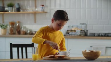 Küçük çocuk mutfakta reçelli sandviç yapıyor. Çocuk yemek pişirmeyi seviyor. Yüksek kalite 4k görüntü