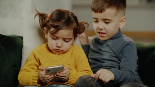 小女孩和甜男孩在没有父母的情况下使用智能手机 兄妹在电话里玩游戏或看卡通片 高质量的4K镜头 — 图库视频影像