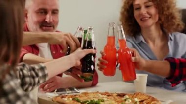 Bir grup işçi masaya oturur ve cam şişelerle bardakları tokuştururlar. Ofis çalışanları öğle arasında pizza yer ve soda içerler. Yüksek kalite 4k görüntü