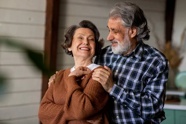 Kaygısız, neşeli, orta yaşlı koca karısını kucaklıyor hayal kuruyor, evde mutluluğun ve aşkın tadını çıkarıyor. Yüksek kalite fotoğraf