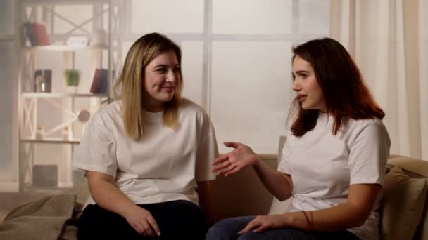 两个年轻女人在家里聊天 两个随意的女性情侣的家庭秘密流言蜚语 新闻流言有很大的乐趣一起在家里的房间 高质量的4K镜头 — 图库视频影像