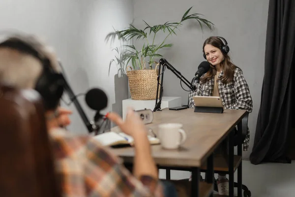 ラジオ労働者はマイクの前のテーブルに座り 一緒に放送します スタジオに座っている間に ヘッドフォンの男と女がポッドキャストを記録します 高品質の写真 — ストック写真