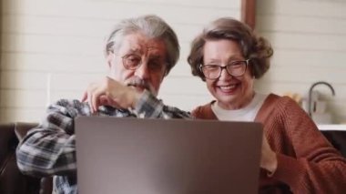 Hoş, olgun bir çift bir adam ve bir kadın dizüstü bilgisayarın başında oturmuş, bir erkeğin saç stilini tartışıyorlar. Yüksek kalite 4k görüntü