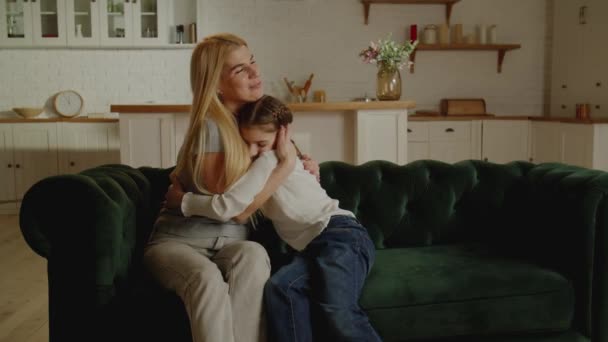 微笑的女儿和迷人的年轻母亲拥抱 享受温馨的时光 表达爱 坐在舒适的沙发上 与家人共度闲暇时光 — 图库视频影像