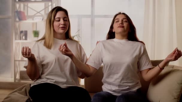 Dos Chicas Jóvenes Que Relajan Sofá Meditando Aliviando Las Emociones — Vídeos de Stock