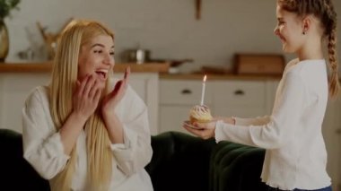 Küçük bir kız, annesini doğum gününde tebrik eder. Sevgili annen için mumlu, neşeli bir kek şeklinde bir sürpriz. Değer verdiğim arzular ve mumu söndürmek. Yüksek kalite