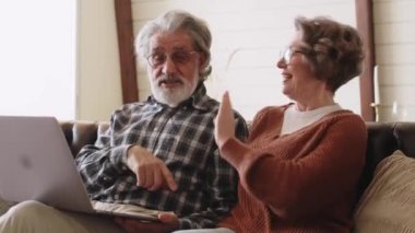 Gülümseyen yaşlı adam ve kadın evdeki bilgisayarlara bakıyorlar. Yüksek kalite 4k görüntü