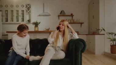 Sarışın anne telefonda konuşuyor ve kızı sürekli onun dikkatini dağıtmak istiyor. Annelerin ve çocukların günlük hayatı. Yüksek kalite 4k görüntü