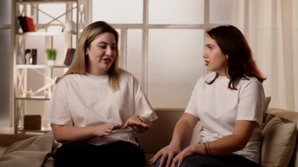 Dwie Młode Dziewczyny Rozmawiają Słodko Siedząc Kanapie Przyjaciele Śmieją Się — Wideo stockowe