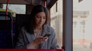 Otobüse binerken akıllı telefon kullanan çekici bir kadın. Genç ve güzel bir kadın toplu taşıma araçlarını kullanıyor. Yüksek kalite 4k görüntü