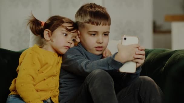 惊奇的孩子们一起看智能手机 快乐的孩子一起使用智能手机 笑着美丽的玩手机 看社交网络上有趣的视频 玩手机游戏 高质量4K — 图库视频影像