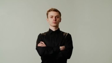 Gri arka planda kolları çapraz duran yakışıklı adam. Adam kollarını göğsünün üzerine kavuşturdu. Yüksek kalite 4k görüntü