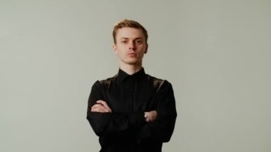 Gri arka planda kolları çapraz duran yakışıklı adam. Adam kollarını göğsünün üzerine kavuşturdu. Yüksek kalite 4k görüntü