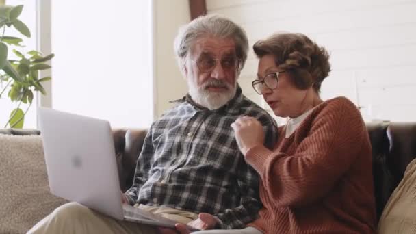 中年の定年退職した家族は コンピュータアプリケーションを使用して インターネットサーフィン オンラインショッピング またはリビングルームの居心地の良いソファで遠くリラックスしたコミュニケーションを楽しんでいます — ストック動画