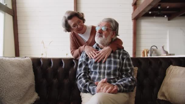 祖父母はソファで笑顔で 老夫婦は幸せな退職で自宅でリラックスします 高齢者の愛 高品質4K映像 — ストック動画