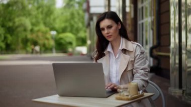 Orta yaşlı bir kadın tatildeyken bir kafede dizüstü bilgisayarla çalışıyor. Öğle yemeği ve kahve beklerken acil bir işim çıktı. Stresli uzaktan kumanda. Yüksek kalite 4k görüntü