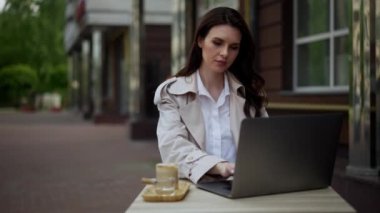 Orta yaşlı bir kadın tatildeyken bir kafede dizüstü bilgisayarla çalışıyor. Öğle yemeği ve kahve beklerken acil bir işim çıktı. Stresli uzaktan kumanda. Yüksek kalite 4k görüntü