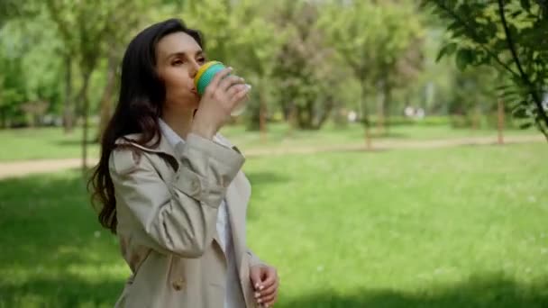 공원에서 코카서스 행복해 있습니다 아름다운 아가씨는 커피를 마시고 공원을 천천히 — 비디오