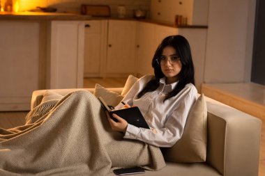 Güzel genç bir kadın not defterine notlar alır. Gözlüklü genç bir esmer kanepeye uzanmış elinde bir not defteri tutuyordu. Yüksek kalite fotoğraf