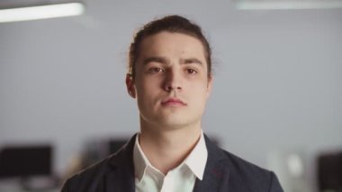 Takım elbiseli, gülümseyen bir adamın yakın plan fotoğrafı. Genç işadamı ofiste dururken gülümseyip kameraya bakıyor. Yüksek kalite 4k görüntü