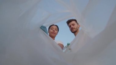 Bir grup çevreci doğadaki çöpleri temizliyor. Doğada plastik bir torba içinde çöp toplayan gençlerin yakın çekimi. Yeşil yaşam ve ekoloji kavramı. Yüksek kalite 4k görüntü