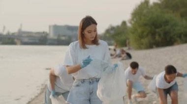 Bir grup çevreci sahildeki çöpleri temizliyor. Gençler doğada plastik bir torba içinde çöp topluyor. Yeşil yaşam, ekoloji ve gezegeni kurtarma kavramı. Yüksek kalite 4k görüntü