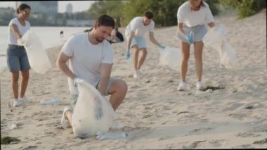 Bir grup çevreci sahildeki çöpleri temizliyor. Gençler doğada plastik bir torba içinde çöp topluyor. Yeşil yaşam, ekoloji ve gezegeni kurtarma kavramı. Yüksek kalite 4k görüntü