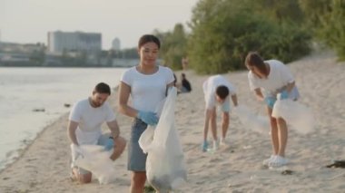 Bir grup çevreci doğadaki çöpleri temizliyor. Doğada plastik bir torba içinde çöp toplayan gençlerin yakın çekimi. Yeşil yaşam ve ekoloji kavramı. Yüksek kalite 4k görüntü