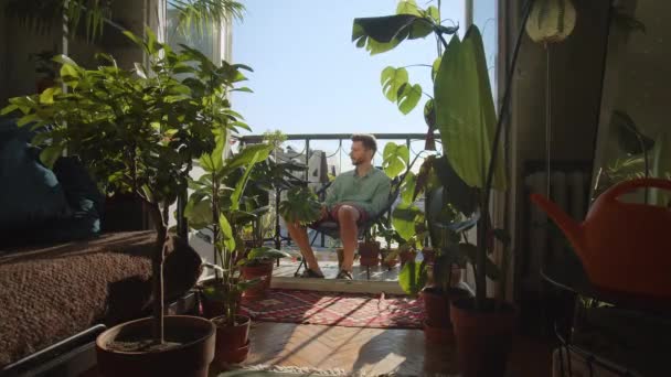 一个年轻人负责照看花 一个男人在家里给花的叶子浇水 植物护理和培育的概念 绿色生态房高质量的4K镜头 — 图库视频影像