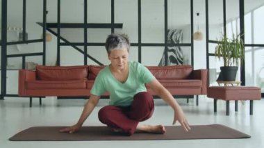 Yaşlı kadın evde yoga egzersizi yapıyor. Olgun kadınlar meditasyon yapar. Yatağa oturur, pencereden dışarı bakar ve dinlenecek vakti olduğuna sevinir. Yüksek kalite 4k görüntü