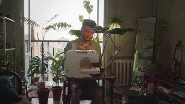 男装设计师在家里的缝纫机上工作 年轻的企业家开始在家里的大绿色工厂的房间里做缝纫生意 手工和制造的概念 高质量4K — 图库视频影像