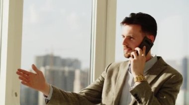 Ofiste çalışan genç bir iş adamı. Mutlu adam telefonla birileriyle konuşuyor. O mutlu. Adam, tatil planları hakkında konuşmak için karısını arıyor. Yüksek kalite 4k görüntü
