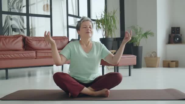 老太太在家做瑜伽运动 成熟的女人有冥想 她闭上眼睛 试图找到内心的集中 快乐的老生活 高质量的4K镜头 — 图库视频影像