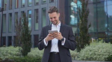 Elinde e-posta tutan şık yakışıklı işadamı sokakta gülümsüyor sosyal ağda mesaj iletileri yazıyor düşünceli adam akıllı telefondaki cep telefonu uygulamasını kullanarak online mağazada malları karıştırıyor.