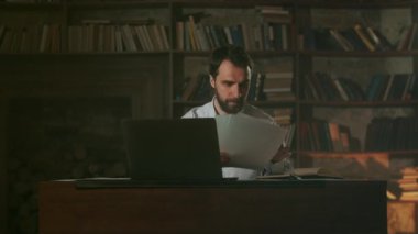 Ofisteki genç adam belgeleri okuyor. İşadamı sözleşmeyi okurken kağıda not alır. Yeni bir iş fikri. Yetenekli adam gece geç saatlere kadar çalışıyor. Kapatın. Yüksek kalite 4k görüntü