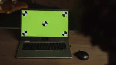 Boş yeşil ekranlı modern bir laptop. Ev içi ya da çatı katı arka planındaki statik görüntüler. Kromakey defter perdesinde. Yüksek kalite 4k görüntü